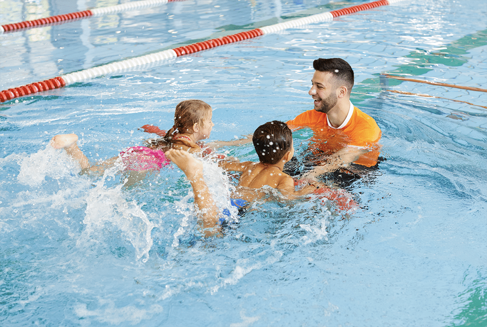 A swim teacher working with two children