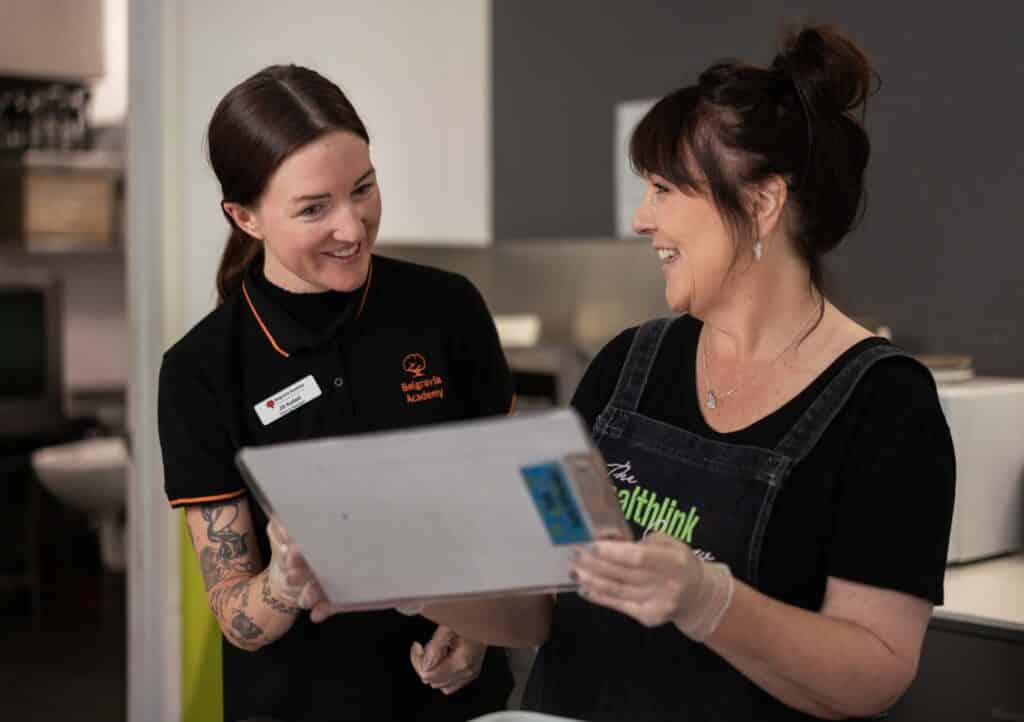 A Belgravia Academy trainer works with a student in a cafe.
